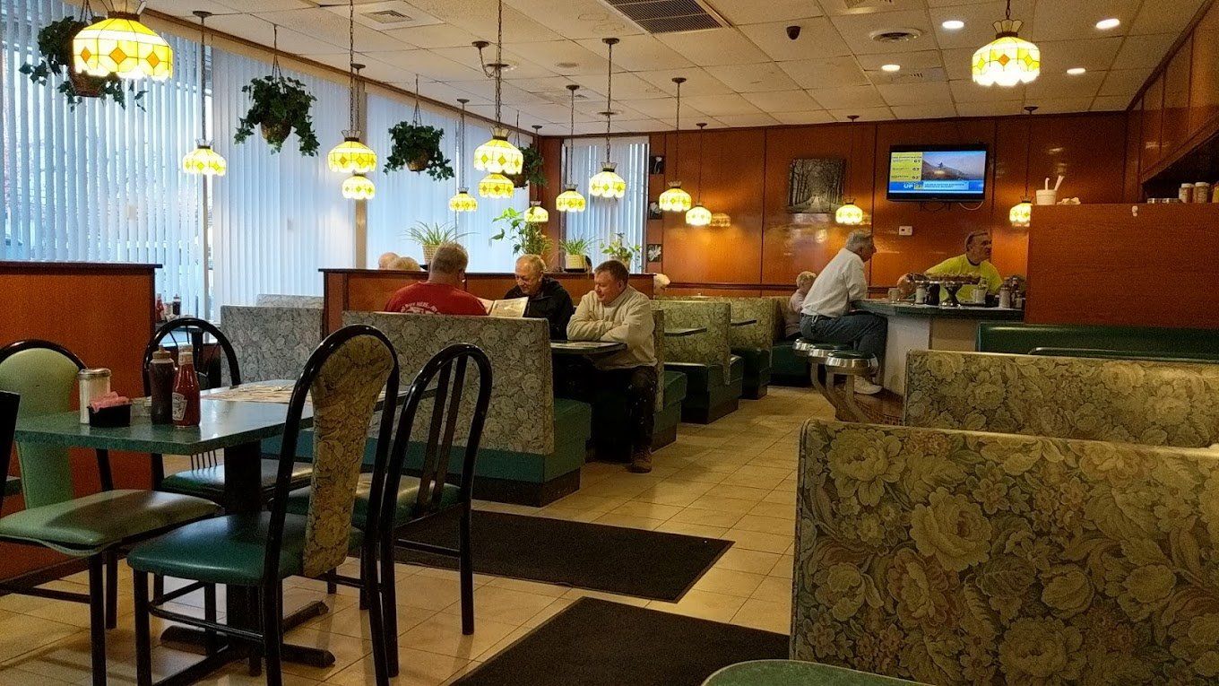 Green booths and tables in the dining room, with amber lamps over the counter